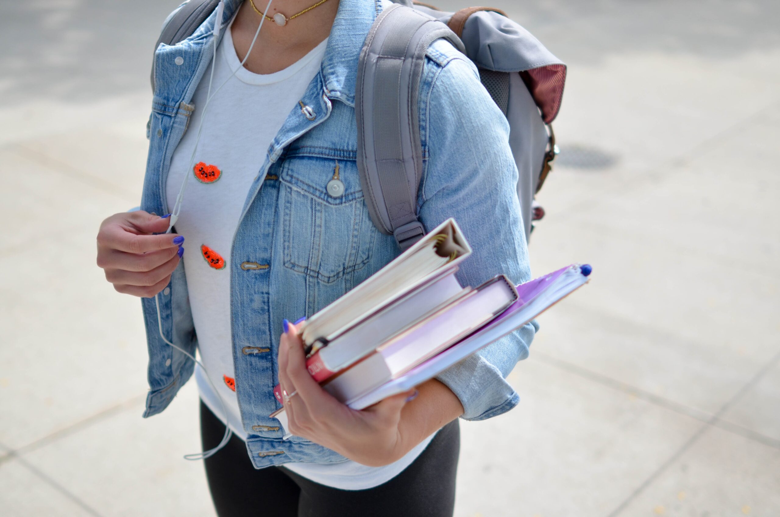 student carrying books and a backpack